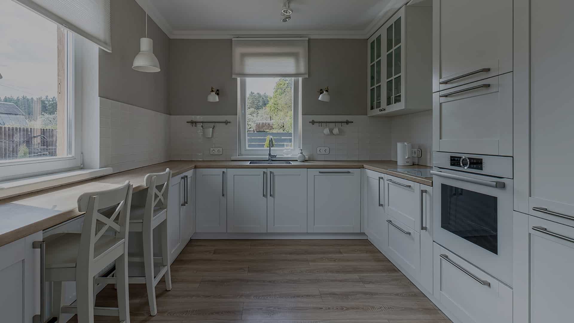 Bright white shaker kitchen with a window, bar stools and a wood countertop