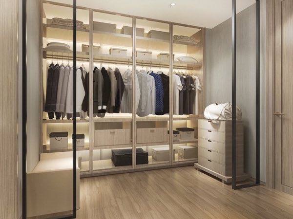Wardrobe with lit shelves behind a glass sliding door