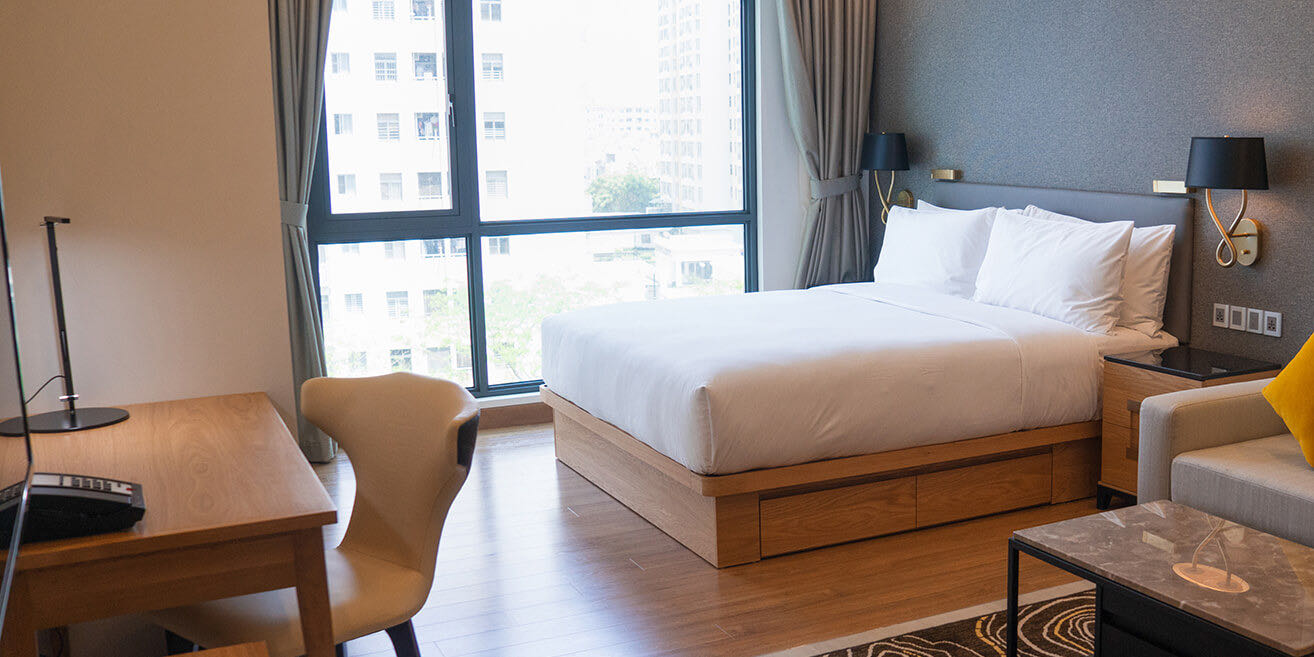 Hotel guest room with a custom wood bed base, desk and nightstand